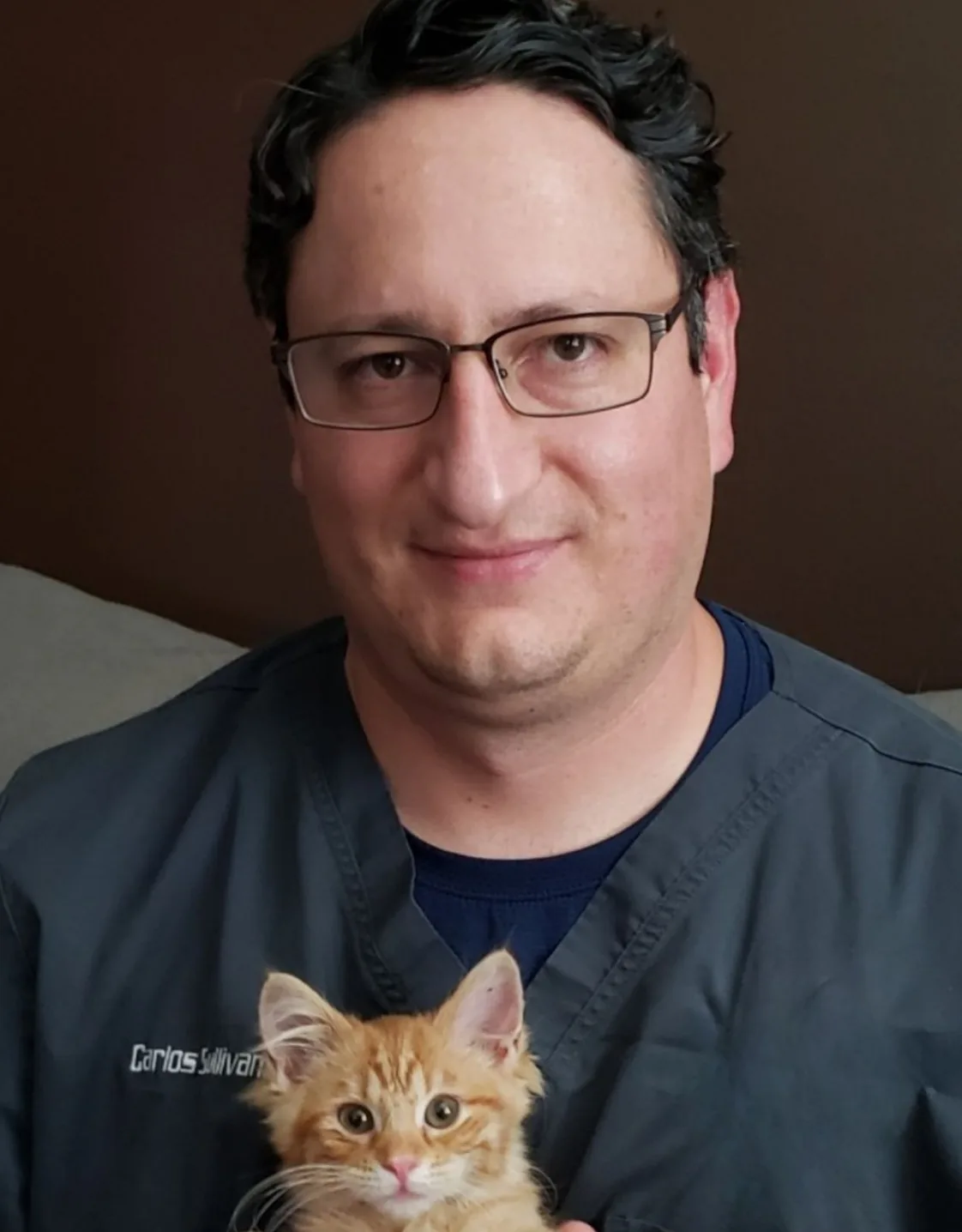 Dr. Carlos Sullivan smiling while holding a kitty. Dr. Carlos Sullivan smiling while holding a kitty.