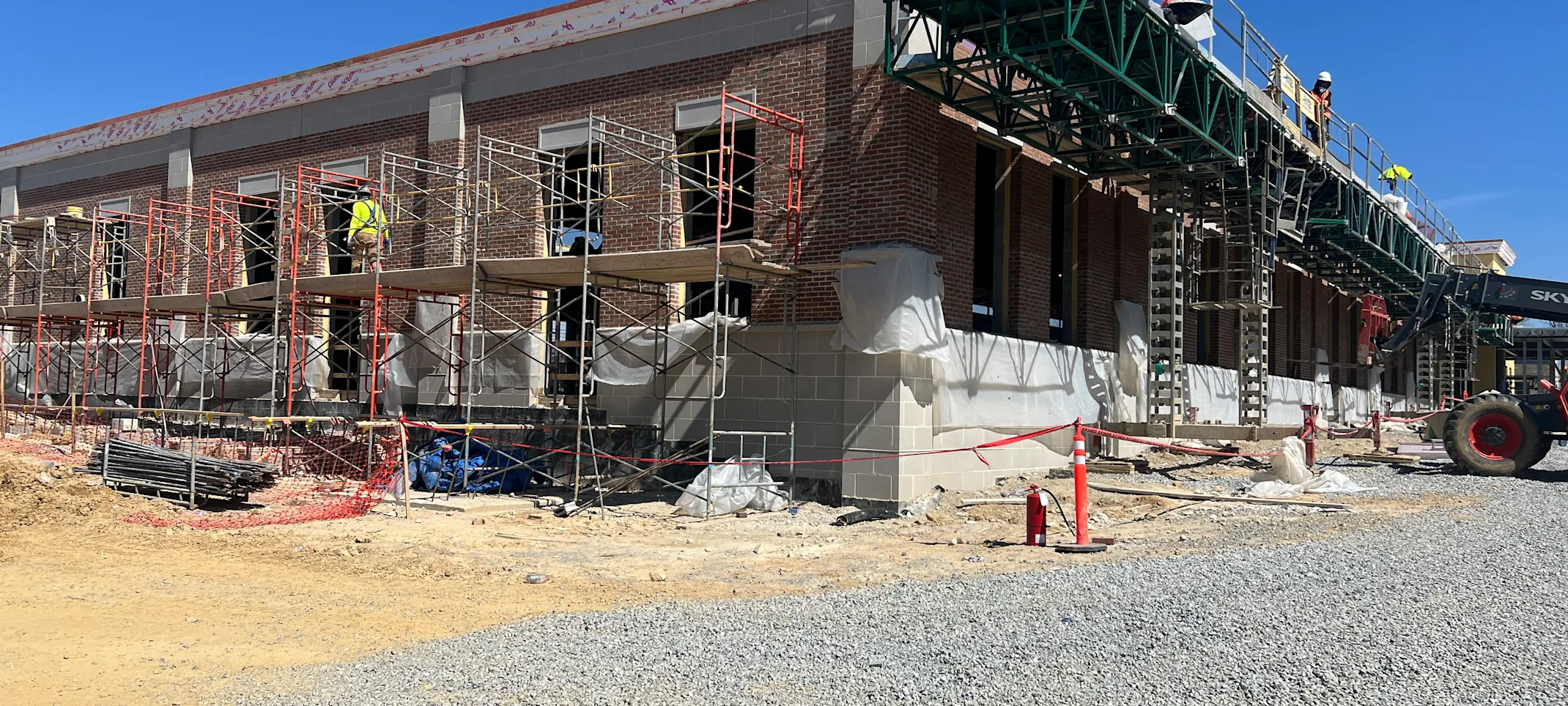 An angle view of the building being constructed with workers working on the ceiling and windows. An angle view of the building being constructed with workers working on the ceiling and windows.