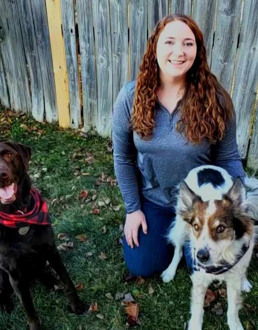 PetSuites Fishers friendly trainer Leanne with two dogs by her side.