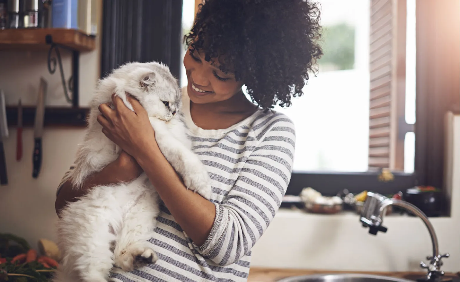 Woman smiling and holding a cat inside Woman smiling and holding a cat inside