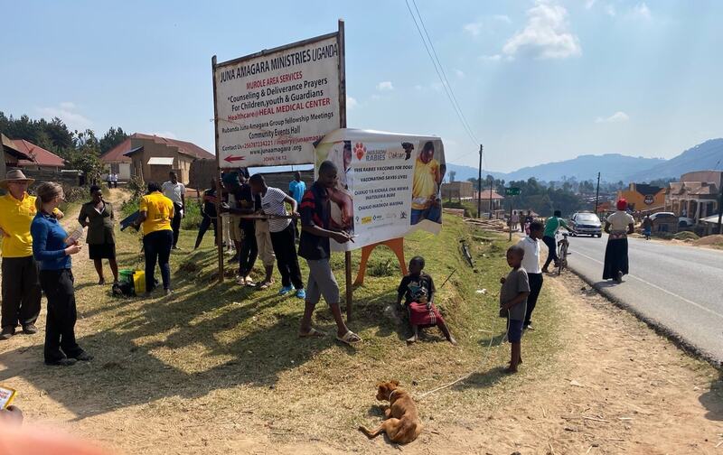 A group of people standing around a Mission Rabies sign