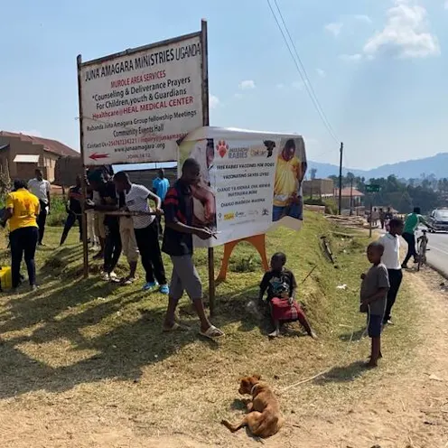 A group of people standing around a Mission Rabies sign A group of people standing around a Mission Rabies sign