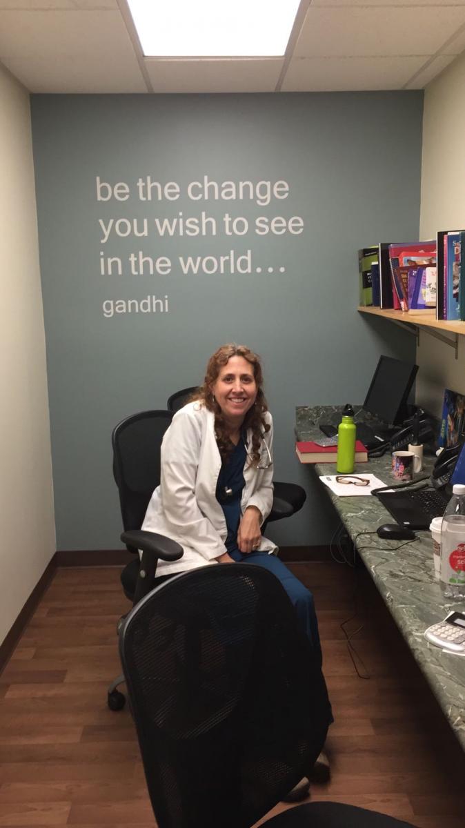 Veterinarian sitting at a row of computers, in front of a wall with a quote on it