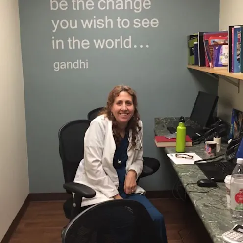 Veterinarian sitting at a row of computers, in front of a wall with a quote on it Veterinarian sitting at a row of computers, in front of a wall with a quote on it