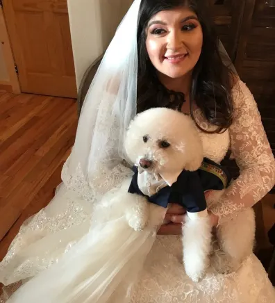 Selena in a wedding dress holding a dog.