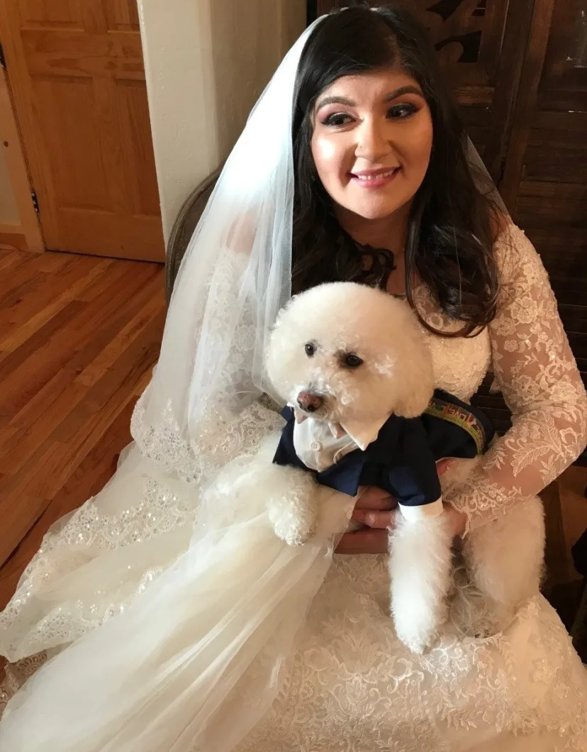 Selena in a wedding dress holding a dog.