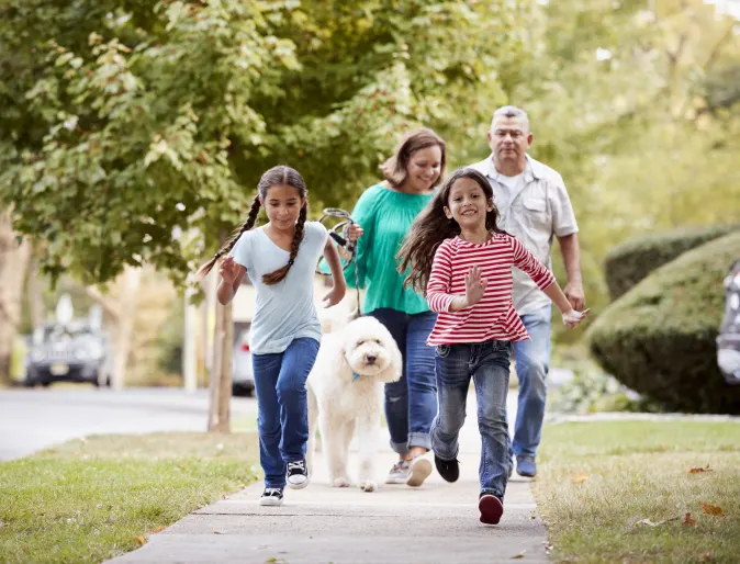 family walking a dog in their neighborhood