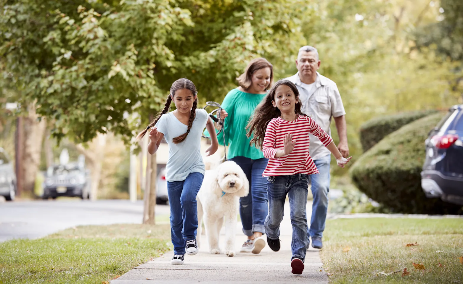 family walking a dog in their neighborhood