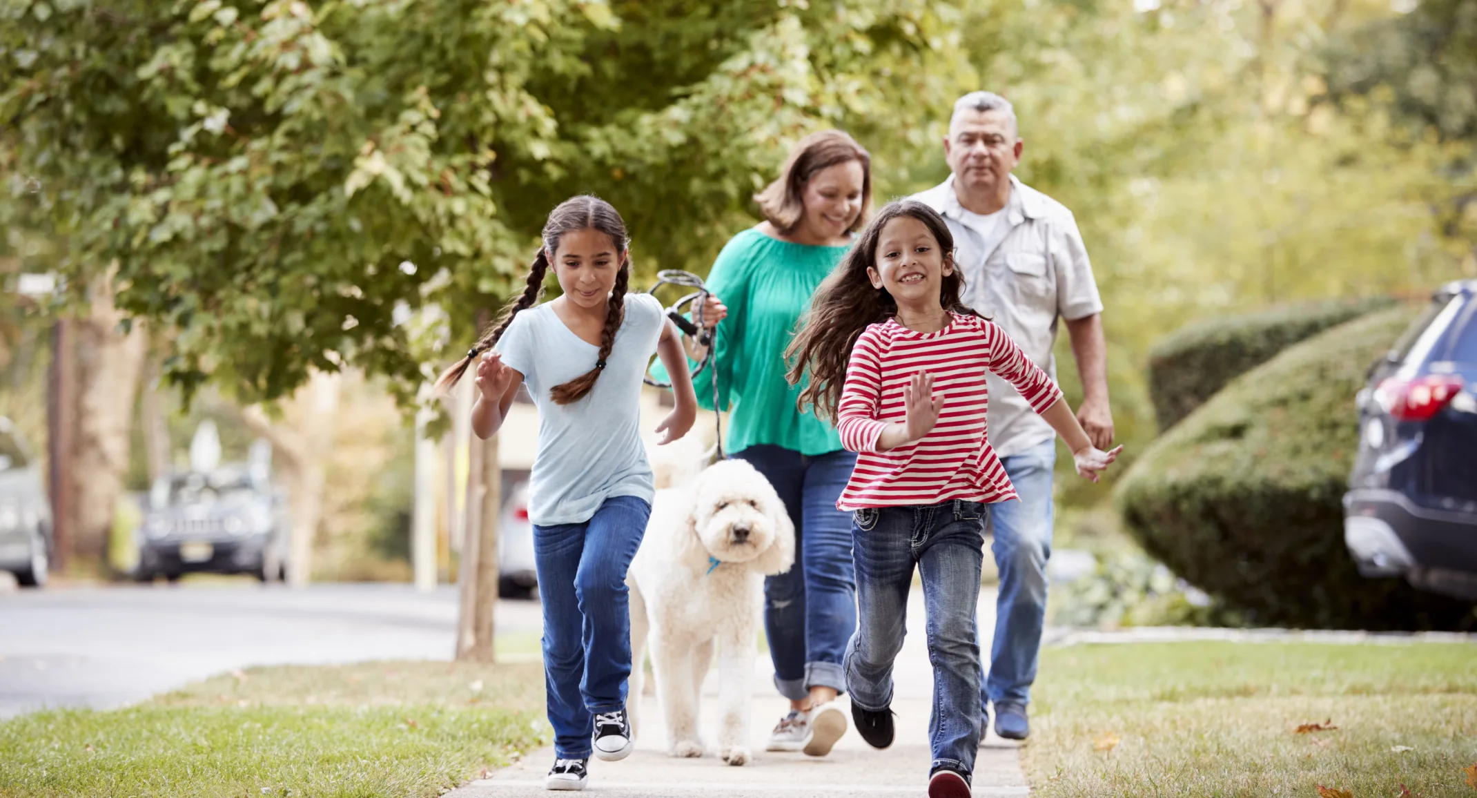 family walking a dog in their neighborhood