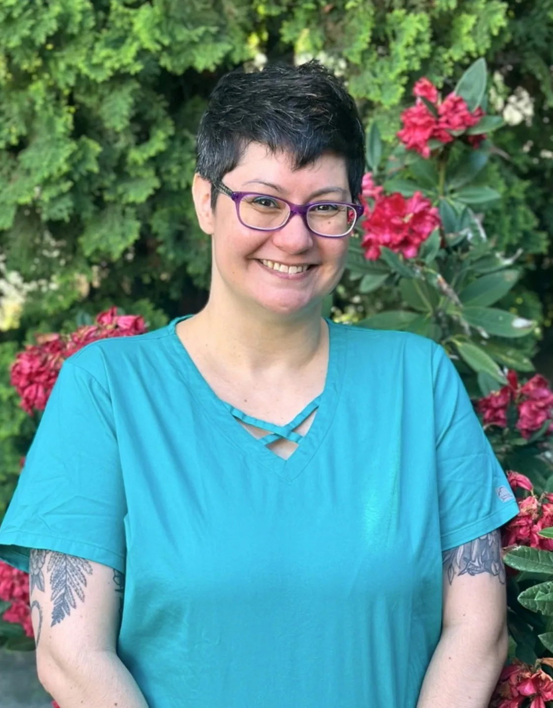 Traci smiling with greenery behind her. Traci smiling with greenery behind her.