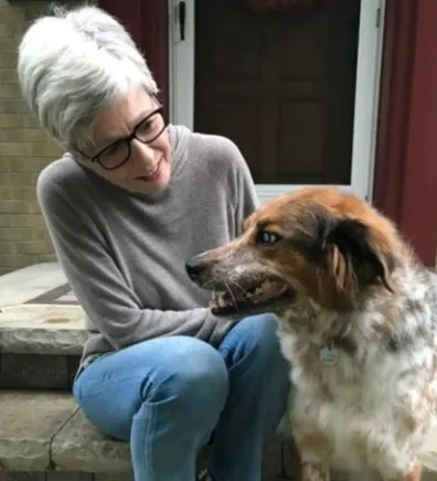 Kim Rourke sitting on steps with a medium-sized dog