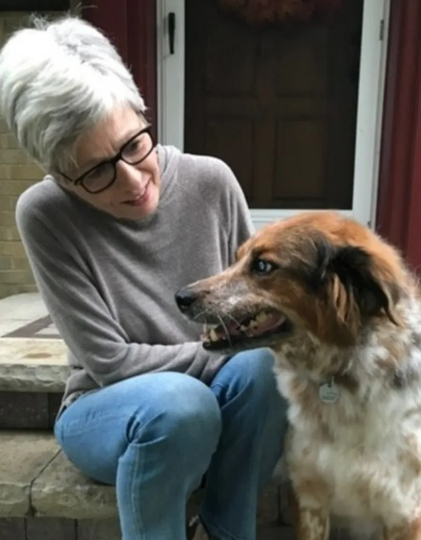 Kim Rourke sitting on steps with a medium-sized dog