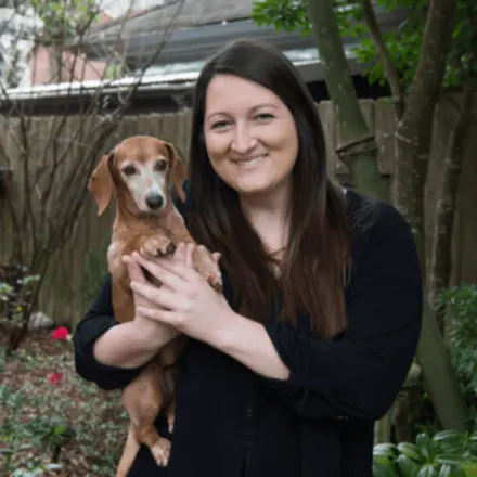 Megan Mayer holding a small brown dog