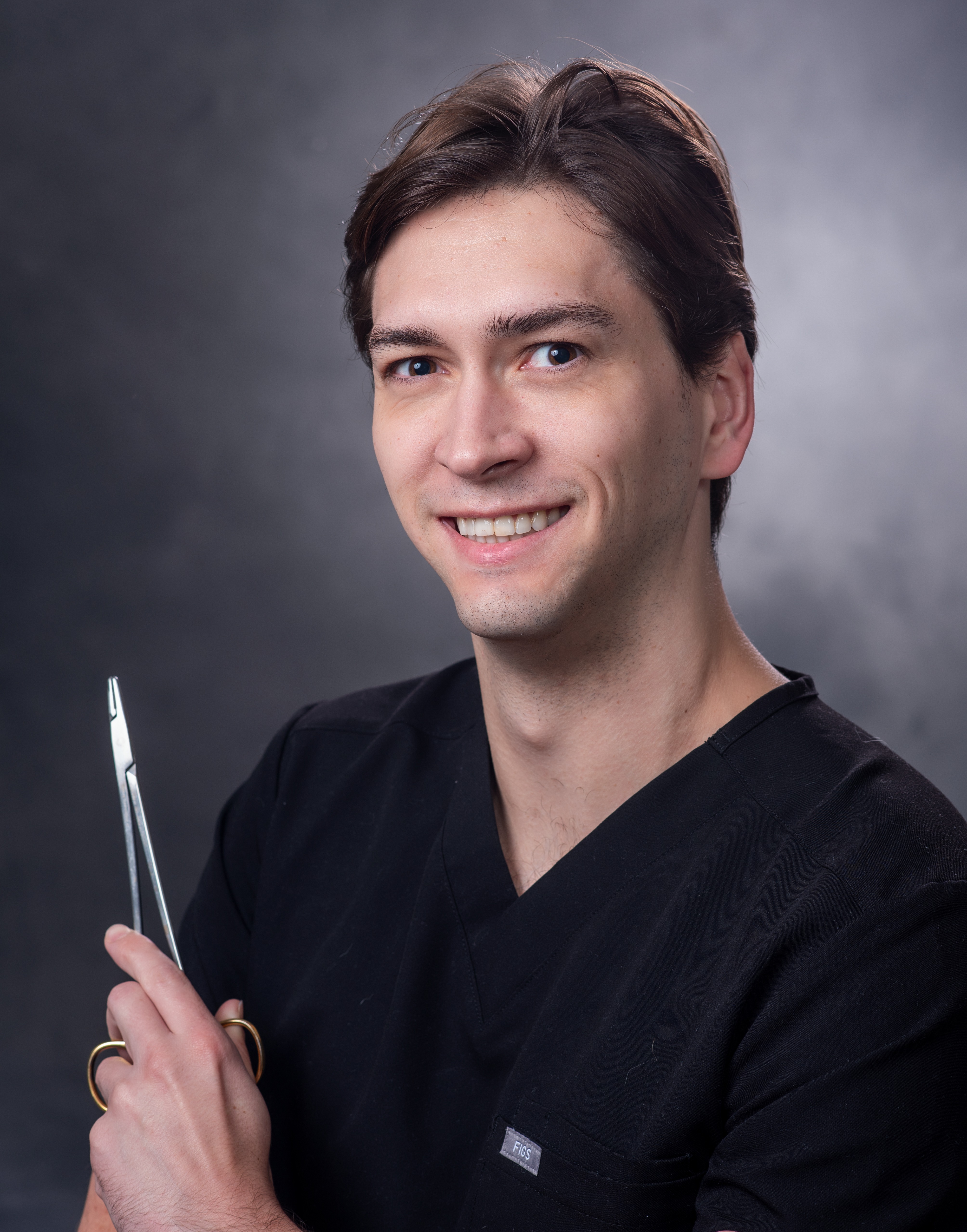Dr. Connor Pynes smiling holding a medical tool