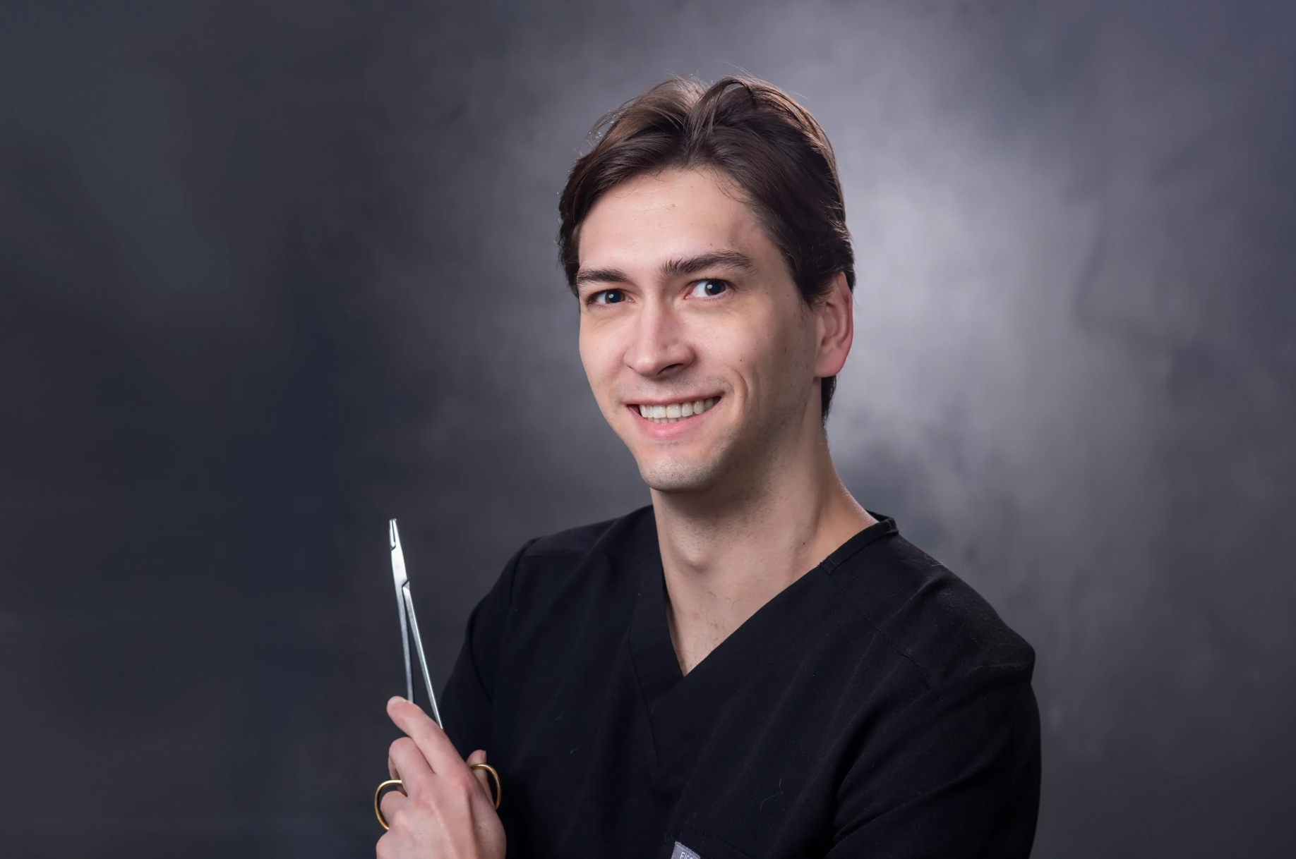Dr. Connor Pynes smiling holding a medical tool