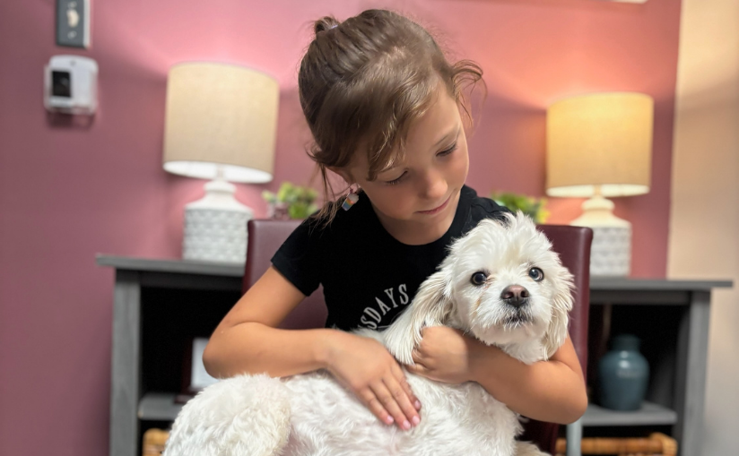 Young girl hugging her white dog