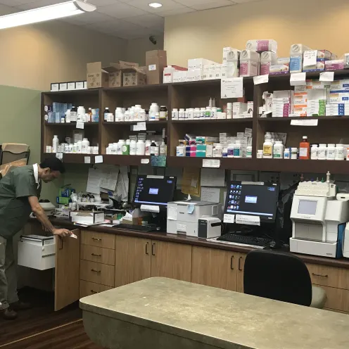 Telegraph Canyon Animal Medical Center's Pet Pharmacy Store that has bunch of pharmacy items on shelves and there's a male staff member looking for an item