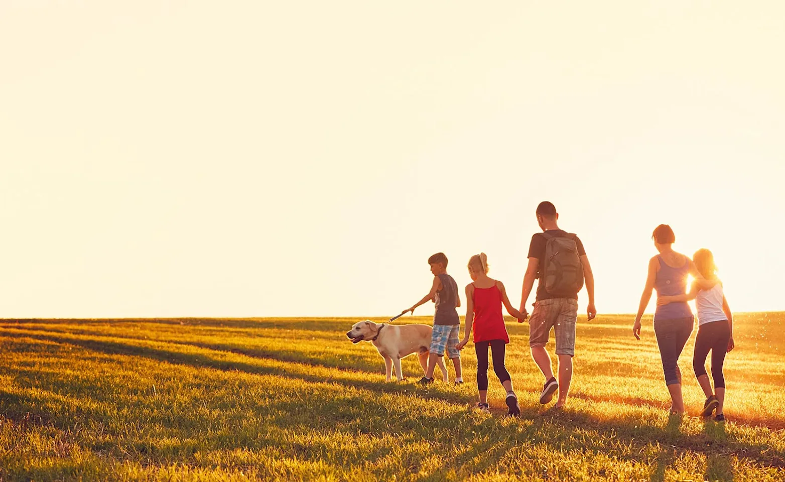 family walking in field with dog