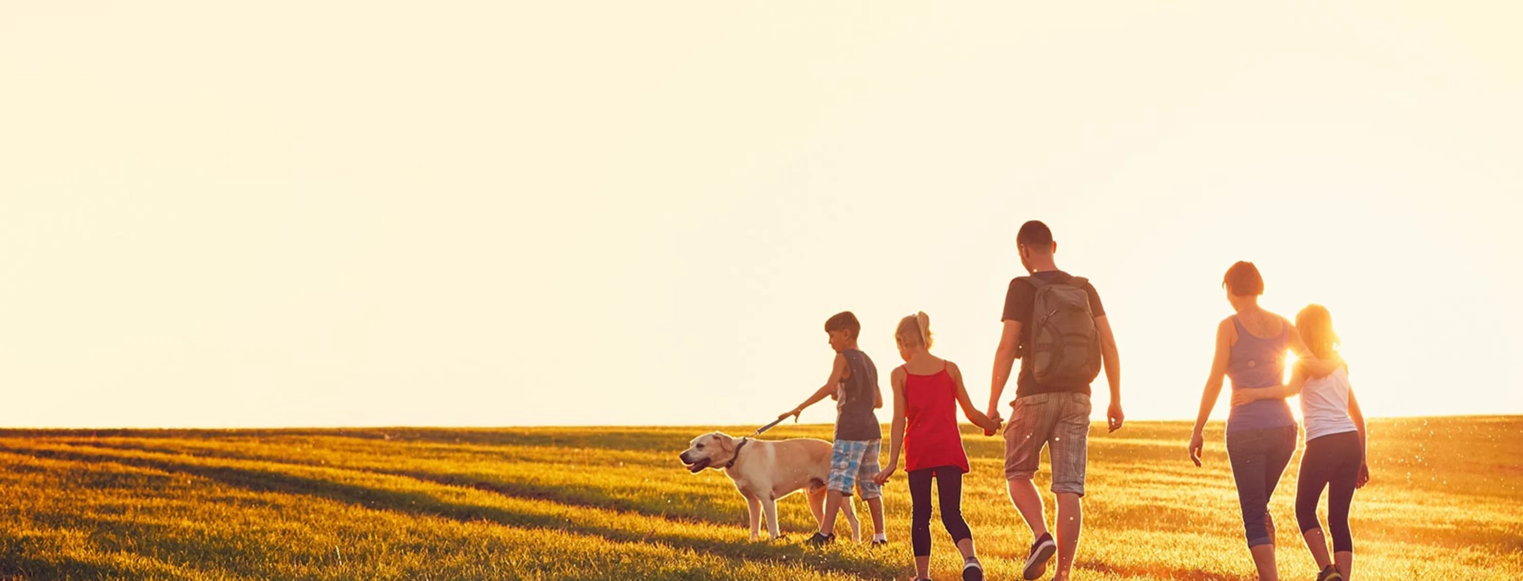 family walking in field with dog