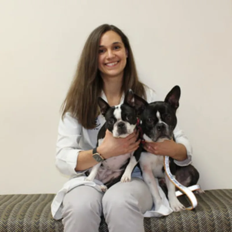 Dr. Alexandra Lynn sitting down while holding two dogs Dr. Alexandra Lynn sitting down while holding two dogs