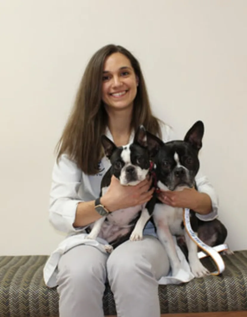Dr. Alexandra Lynn sitting down while holding two dogs