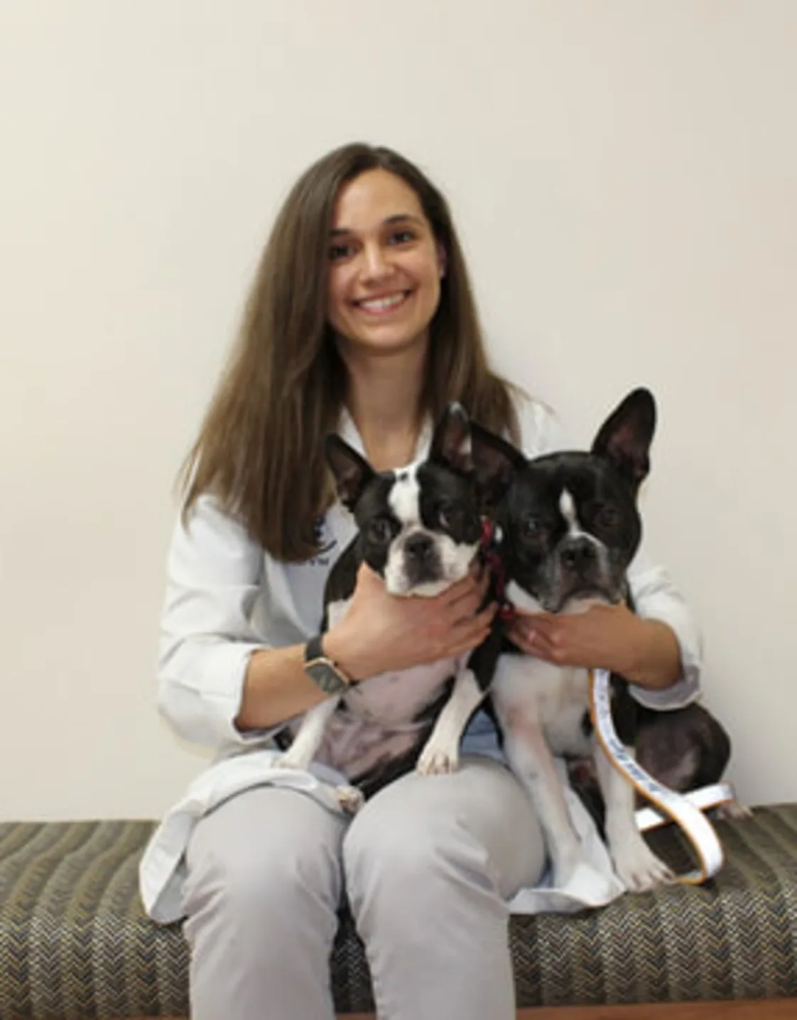Dr. Alexandra Lynn sitting down while holding two dogs Dr. Alexandra Lynn sitting down while holding two dogs