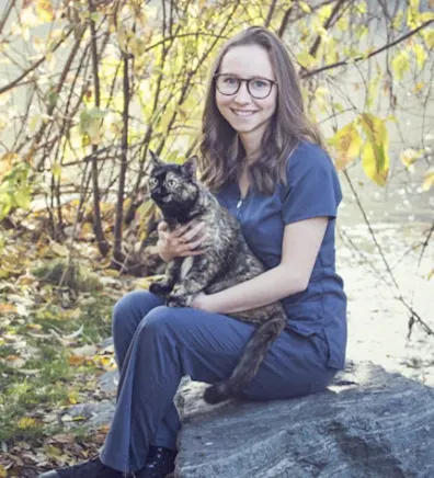Natalie sitting on a rock and holding a brindle cat Natalie sitting on a rock and holding a brindle cat