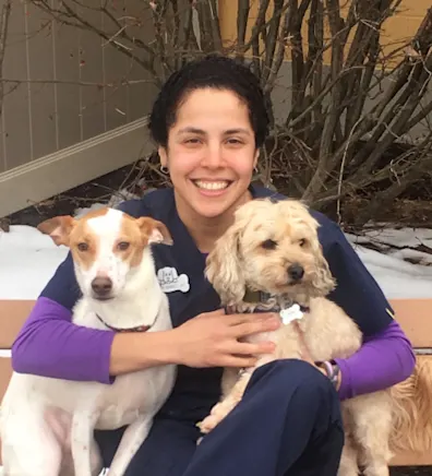 Jeileen sitting on a bench while holding two dogs Jeileen sitting on a bench while holding two dogs