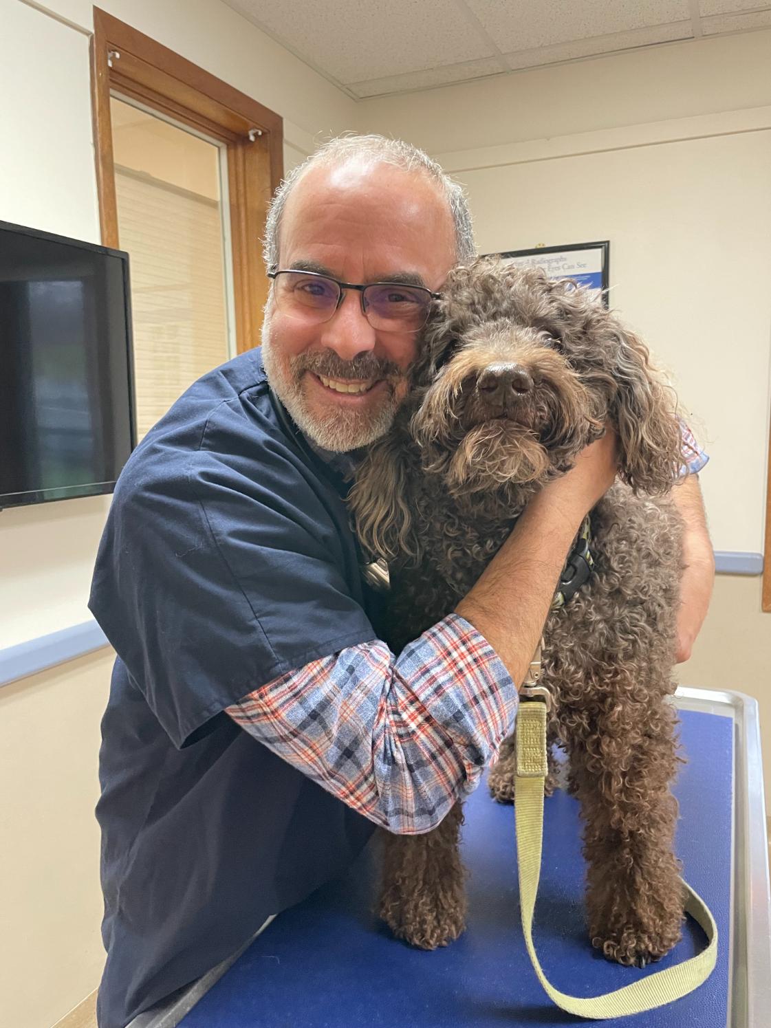 Pete hugging a brown dog on a leash
