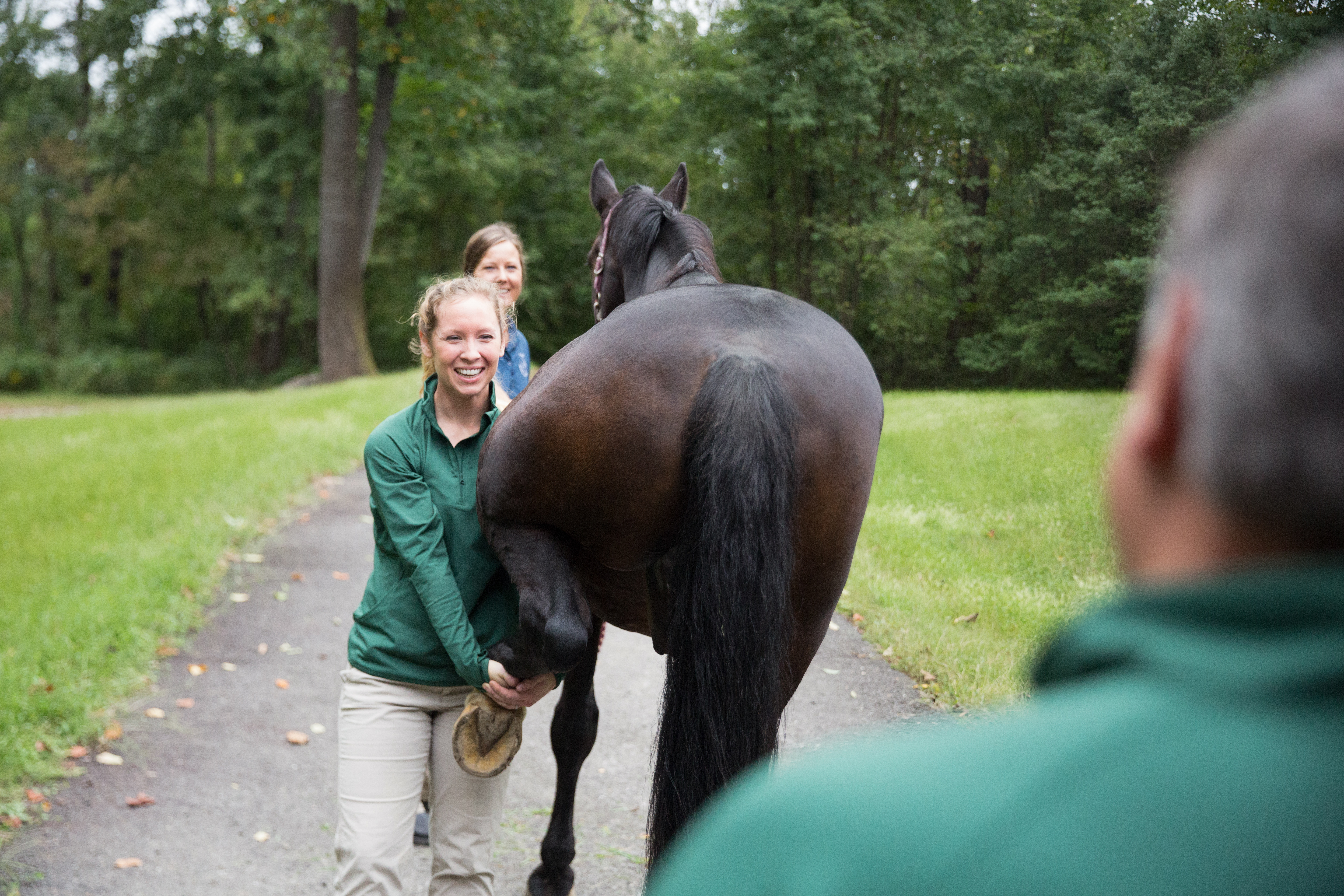a vet holding a horse's backleg while looking at the camera