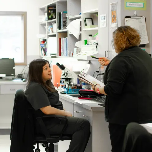 Two nurses in black scrubs are going over their medical checklist in their Poulsbo Marina Veterinary Clinic Lab.