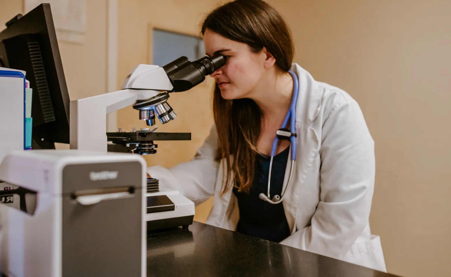 A MAB team member looking at a sample through an advanced microscope A MAB team member looking at a sample through an advanced microscope