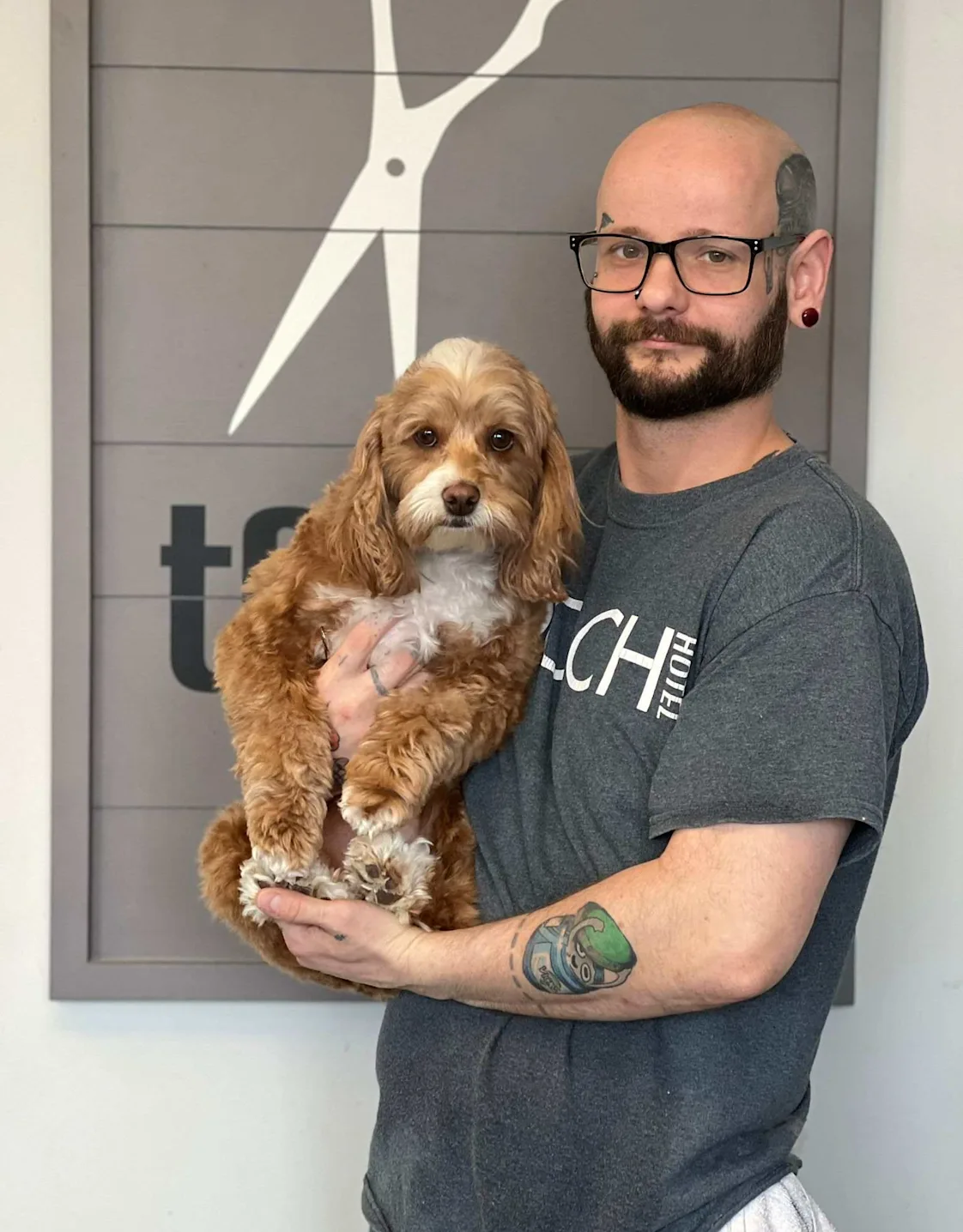 Max, groomer at Pooch Hotel, holding a dog Max, groomer at Pooch Hotel, holding a dog