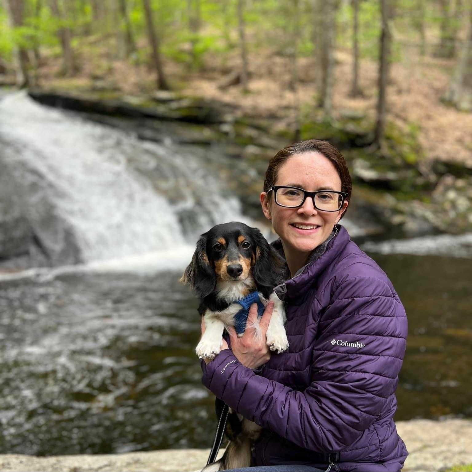 Misty standing next to a tree while holding a dog