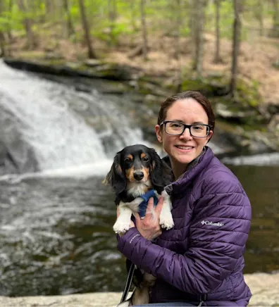 Misty standing next to a tree while holding a dog Misty standing next to a tree while holding a dog