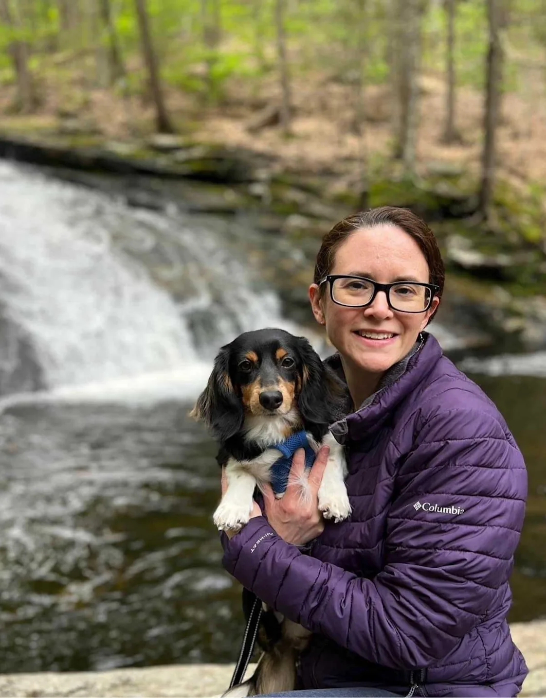 Misty standing next to a tree while holding a dog Misty standing next to a tree while holding a dog
