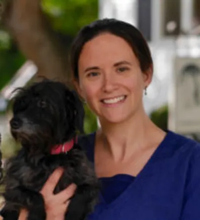 Misty standing next to a tree while holding a dog Misty standing next to a tree while holding a dog