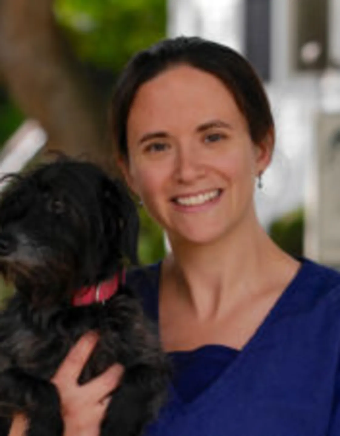 Misty standing next to a tree while holding a dog Misty standing next to a tree while holding a dog