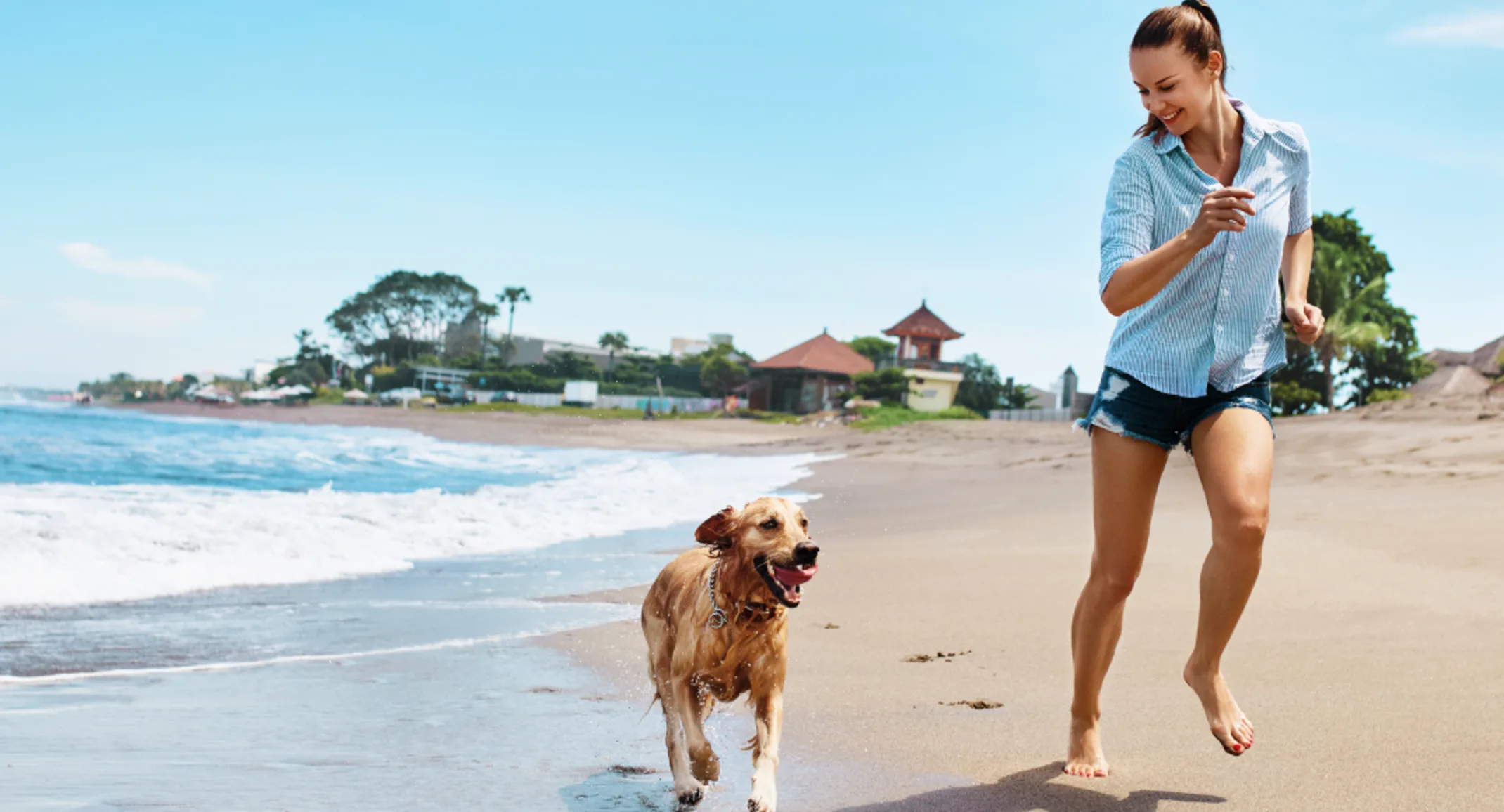 Women and dog running on the beach with waves Women and dog running on the beach with waves