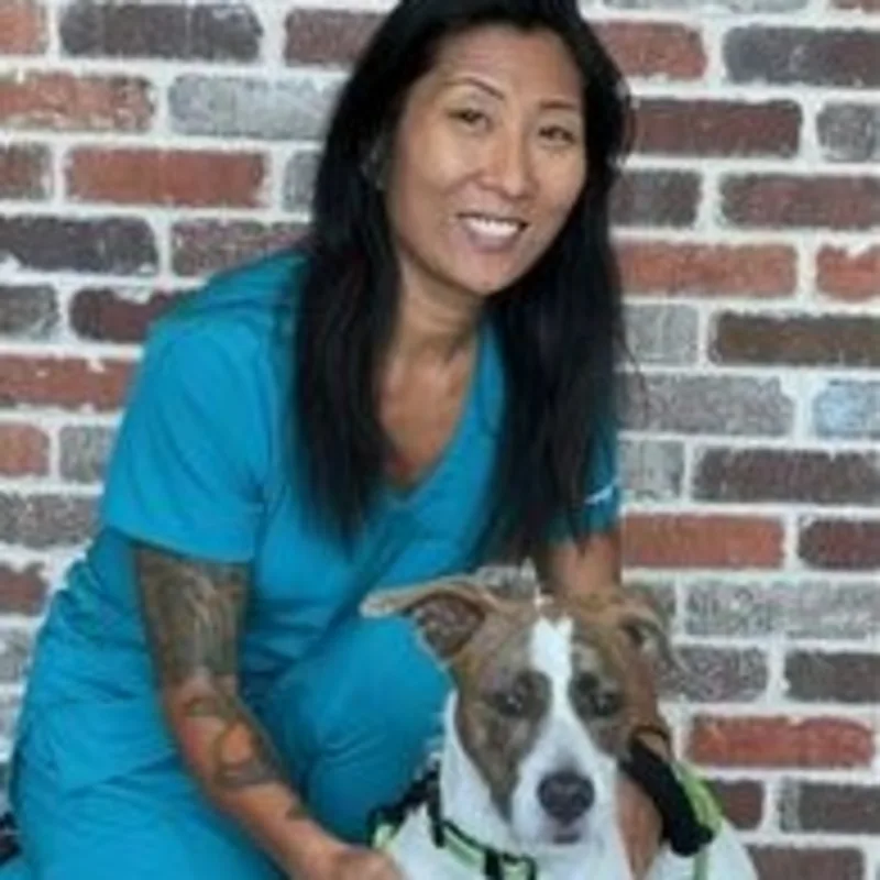 Amy Kunde kneeling next to a white and brown dog Amy Kunde kneeling next to a white and brown dog