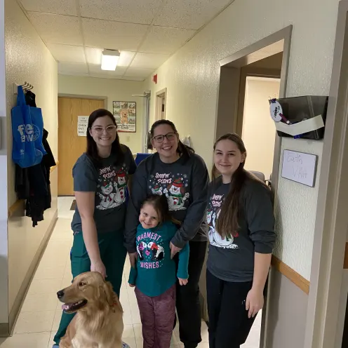Staff in Christmas shirts with a golden retriever. 