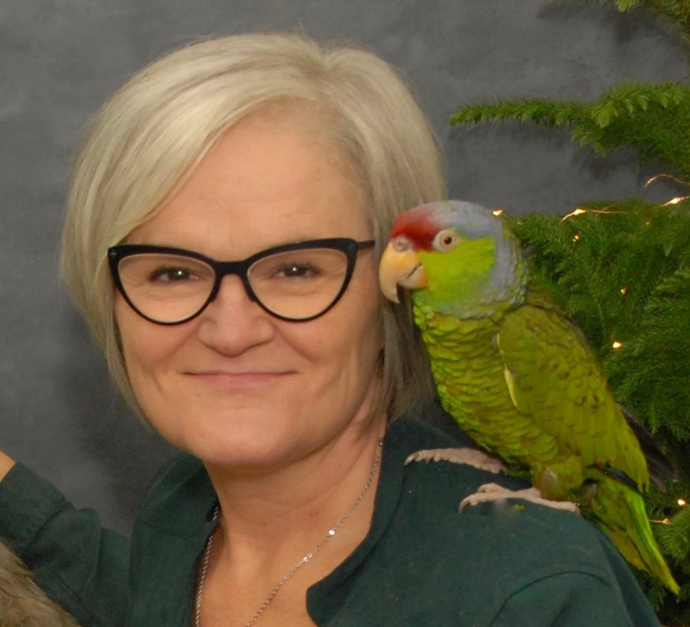 Sandra McBride smiling with her Lilac Crowned Amazon on her shoulder