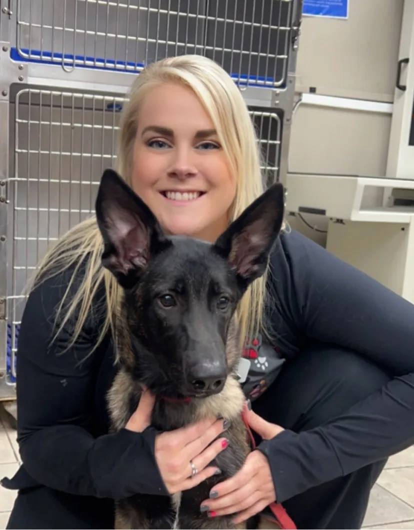Katie, veterinary technician, posing with a black dog