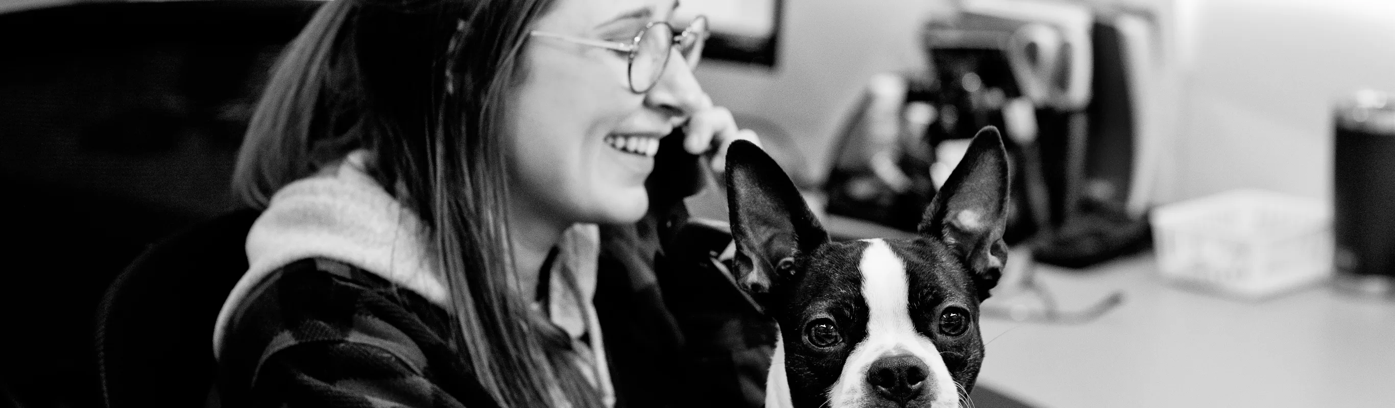 Black and white photo of an Eagleview Veterinary Hospital staff member on the phone with a dog.