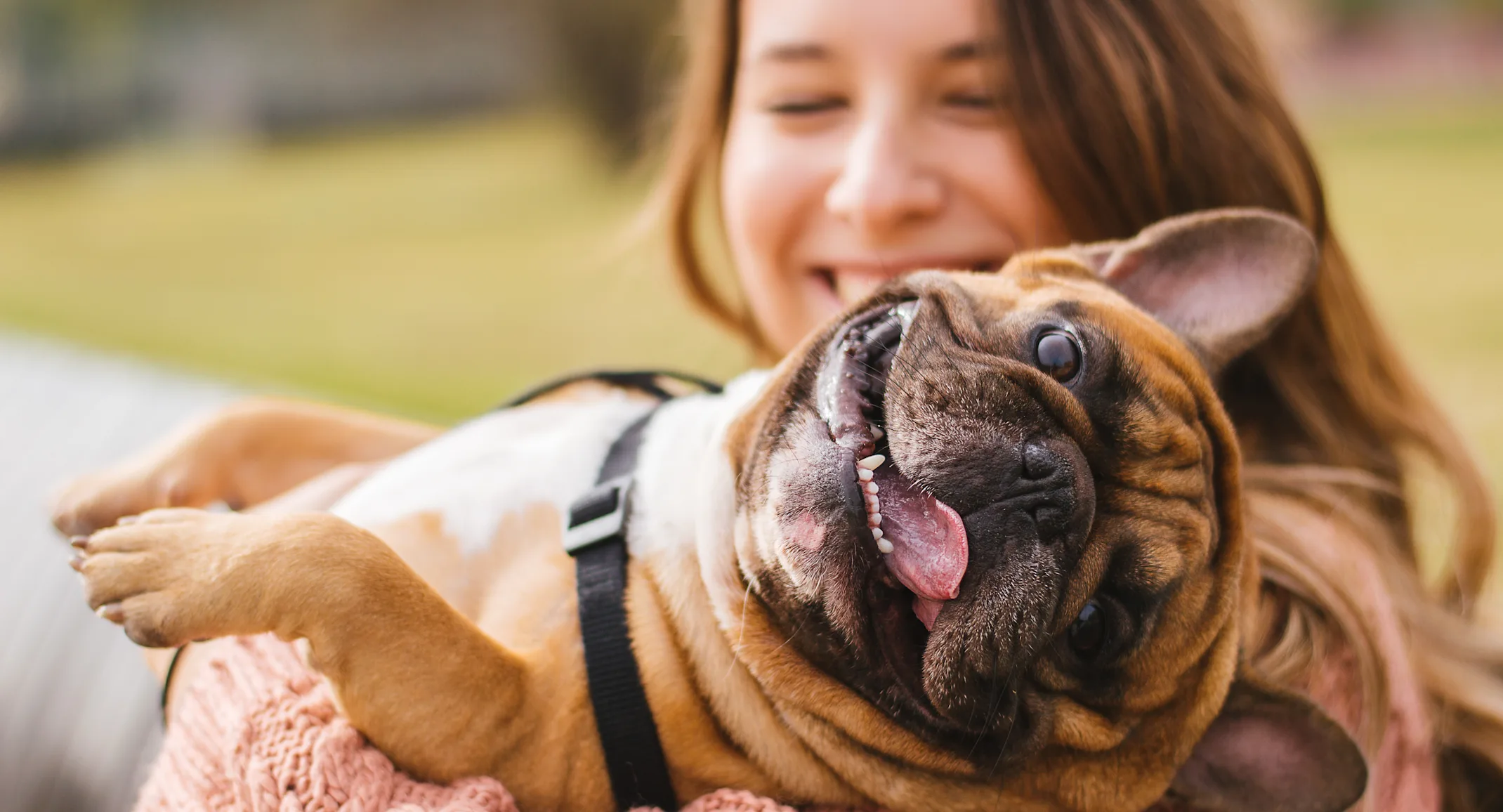 Women holding dog over shoulders as the dogs tongue is out