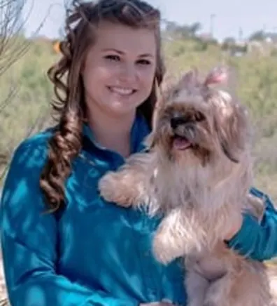 Jackie wearing blue and holding a dog. Jackie wearing blue and holding a dog.