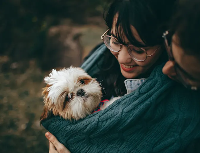 Young couple hugging their shih tzu pup Young couple hugging their shih tzu pup