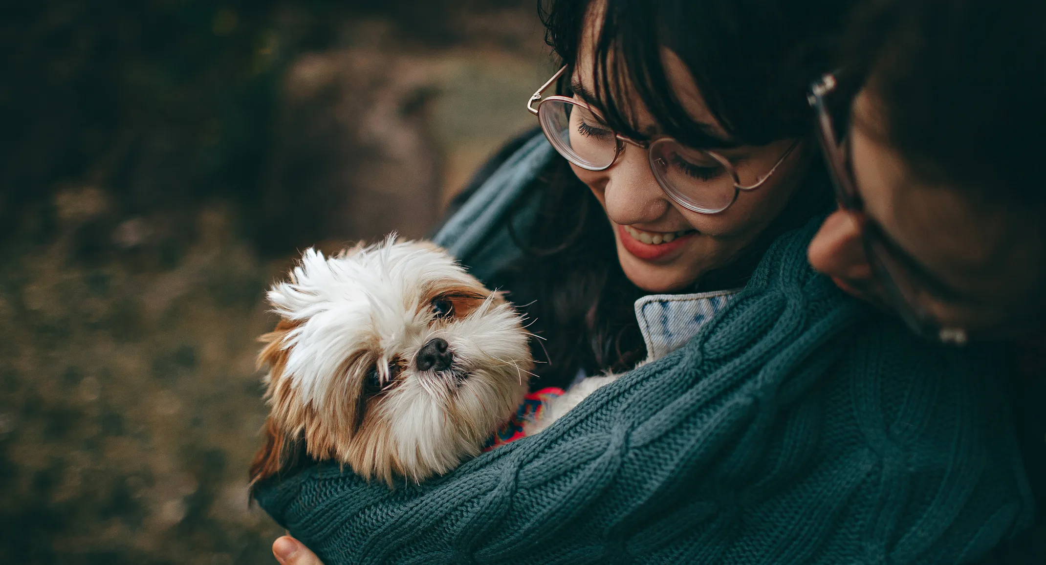 Young couple hugging their shih tzu pup Young couple hugging their shih tzu pup