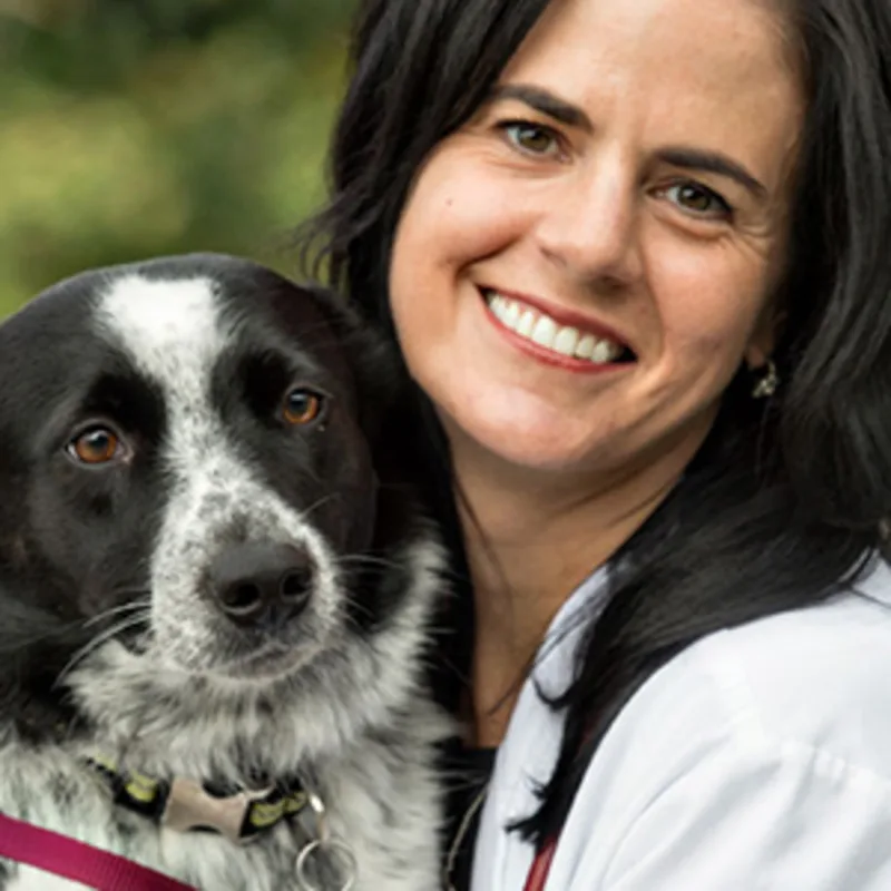Andrea Wells smiling hugging a black and white dog Andrea Wells smiling hugging a black and white dog