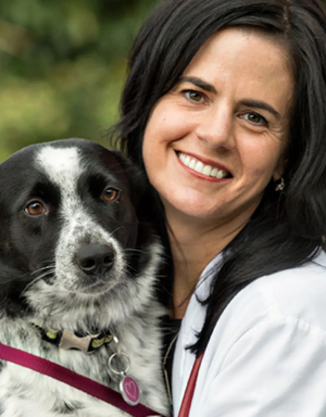 Andrea Wells smiling hugging a black and white dog Andrea Wells smiling hugging a black and white dog